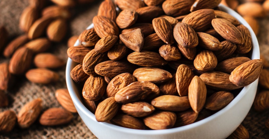 Almonds overflowing from a white bowl.