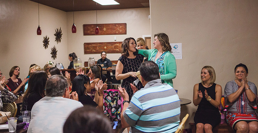 Restaurant crowded with women, two speaking emotionally at a microphone