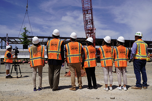 Chancellor Leland and others look on as the final beam of the 2020 Project is raised.