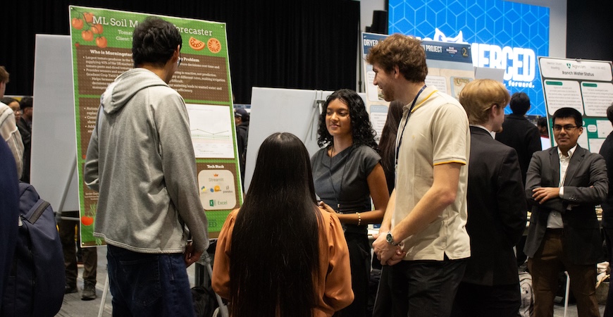 UC Merced students are depicted in front of a poster explaining their project for I2G.