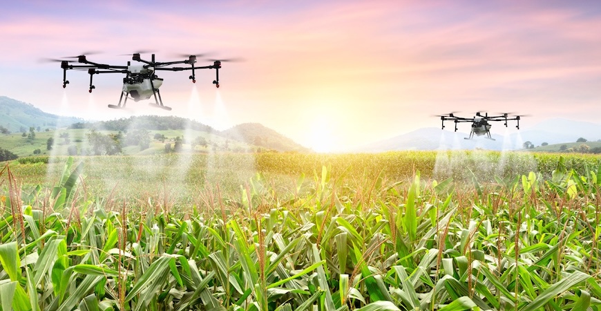 Photo depicts drones delivering water to crops.